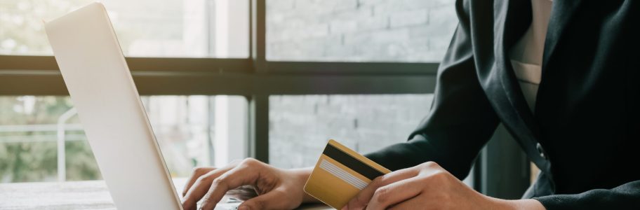 Online payment,Business woman's hands holding a credit card and using laptop computer for online shopping with vintage filter tone